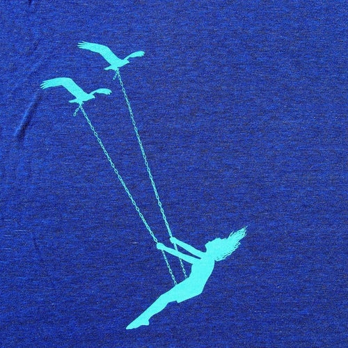 Blue t-shirt with a design of a woman on a swing and two birds on a blue background