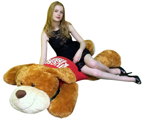 Woman sitting on a large brown teddy bear with a red dress and white text.