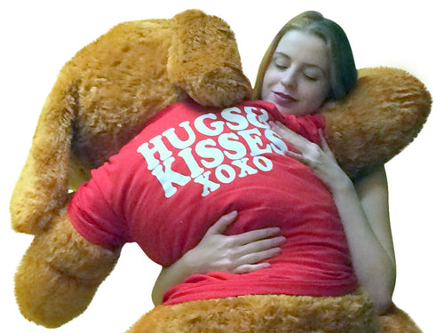 Person wearing a red shirt with 'HUGS KISSES XOXO' text, embraced by a large teddy bear.