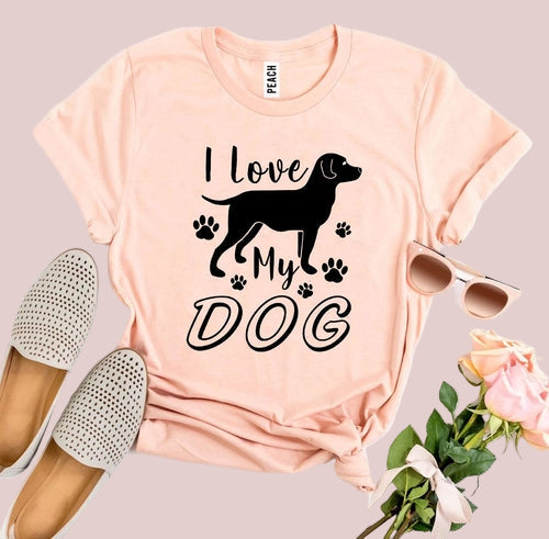 Pink t-shirt with 'I Love My Dog' graphic, sunglasses, loafers, and flowers on a white background