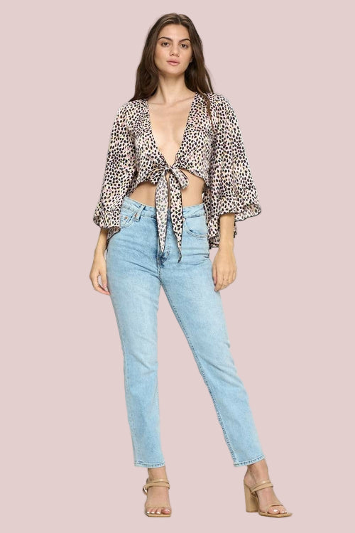 Woman wearing a leopard print top and light blue jeans on a white background