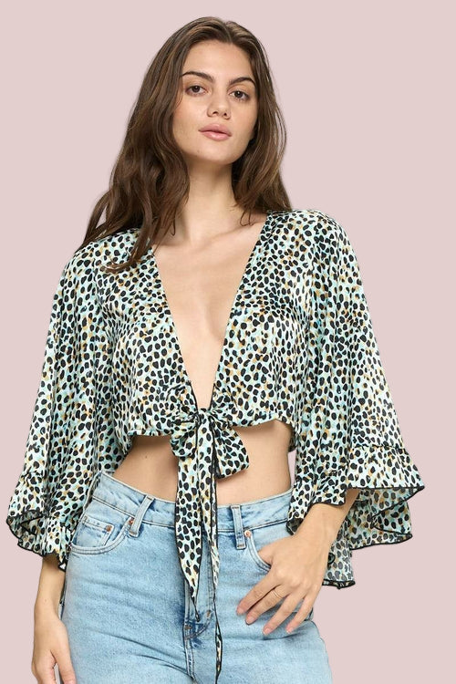 Woman wearing a leopard print top and blue jeans on a white background