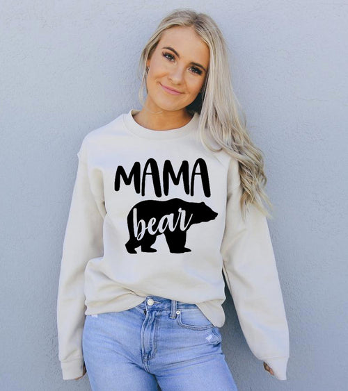 Woman wearing a white sweatshirt with 'MAMA bear' text and black bear graphic against a light gray background
