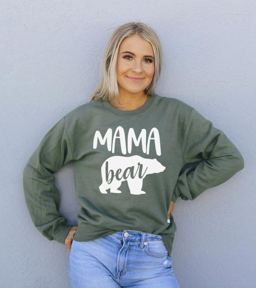 Woman wearing a green 'Mama bear' sweatshirt against a light gray background