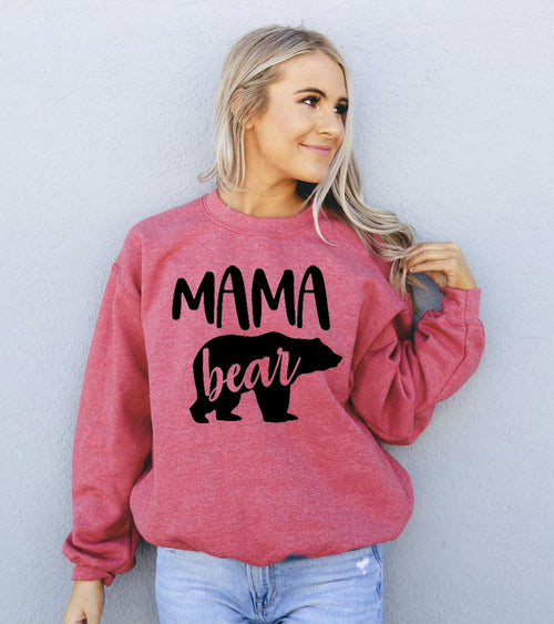 Woman wearing a pink sweatshirt with 'MAMA bear' text against a light gray background