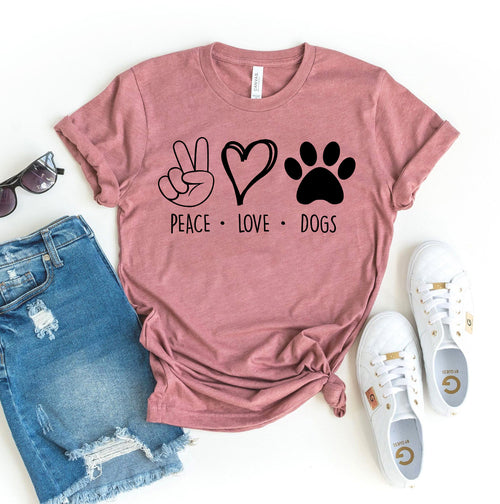 Pink t-shirt with 'Peace Love Dogs' graphic, paired with denim shorts and white sneakers on a white background.