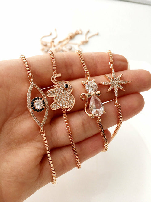 Rose gold necklaces with various pendants held in a hand against a white background
